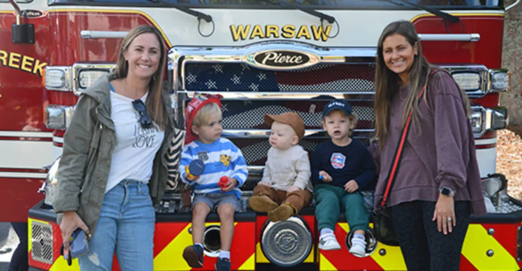 Two women with children in front of a fire truck